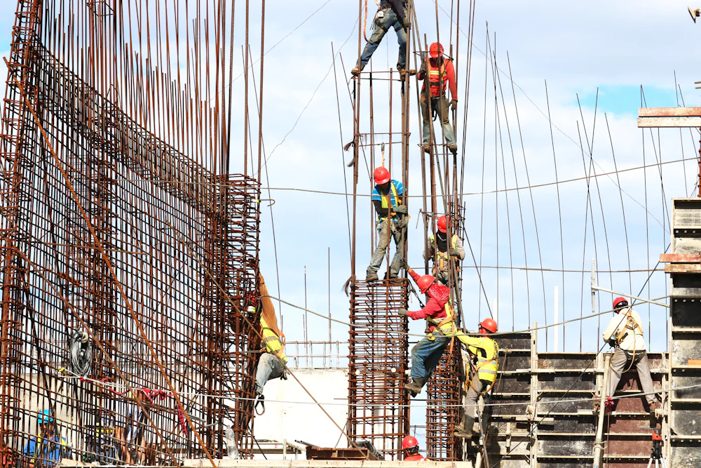 Construction workers in hard hats tying reinforcement steel for concrete columns